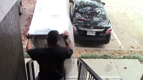 mover carrying a wrapped mattress up apartment stairs