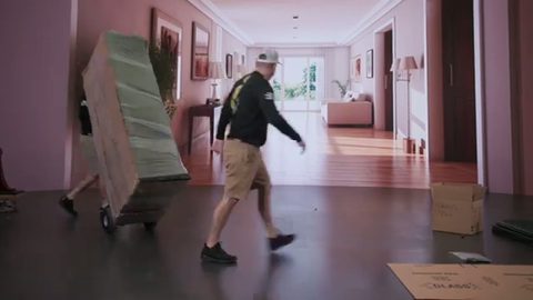 mover wheeling a blanket-wrapped buffet on a hand truck down a hallway