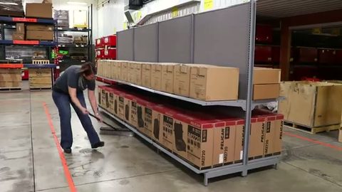 mover moving a loaded retail shelving unit with a pry bar in a warehouse